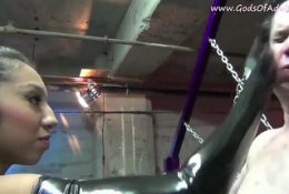 Asian mistress in latex slaps a slave and spits in his mouth.